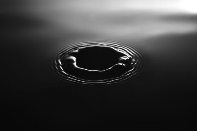 Abstract water ripple pattern creating concentric circles on a black background. Perfect for use in design projects, backgrounds, posters, or wallpapers to convey themes of calmness, fluidity, and minimalism.