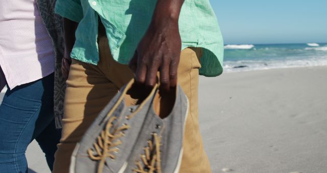 People walking on sunny beach holding shoes - Download Free Stock Images Pikwizard.com