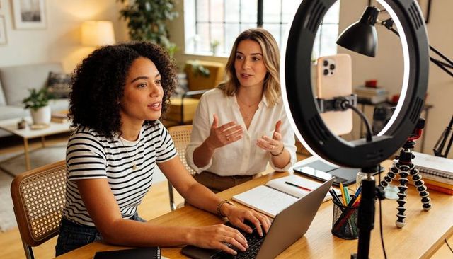 Creators collaborating on laptop with ring light for livestream and podcast production