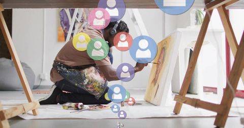 Focused artist painting in bright studio with headphones