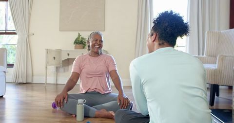 Senior woman practicing yoga at home with instructor for wellness