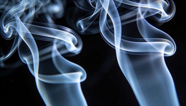 Swirling Luminous Blue Smoke Ribbons Rising Over Deep Black Background