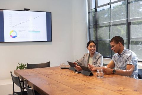 Diverse professionals discussing business analytics on tablets