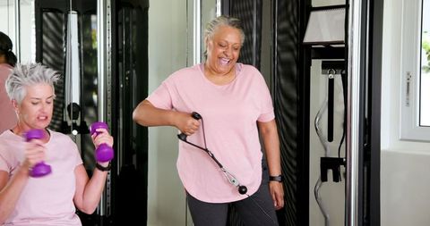 Happy senior couple exercising with weights in contemporary home gym