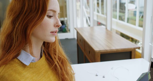 Woman with Red Hair Examining Device in Modern Office Space - Download Free Stock Images Pikwizard.com