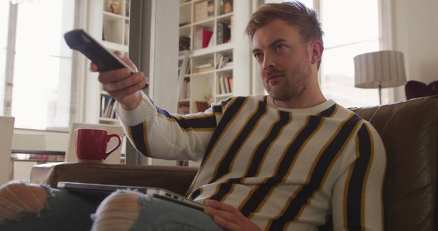 Young man using remote control in living room - Download Free Stock Images Pikwizard.com