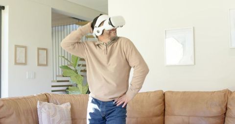 Mature Asian Man Standing Living Room Adjusting VR Headset