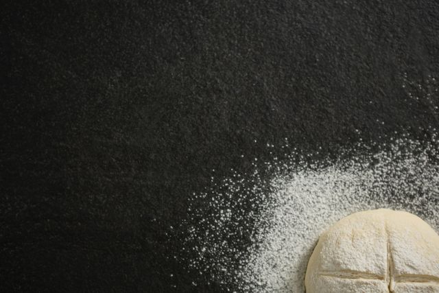 Cropped image of flour on unbaked bun at table
