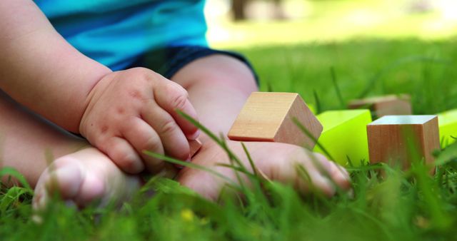 Baby playing with building blocks on the grass on a sunny day
