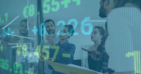 Team Collaborating Over Stock Market Data on Glass Wall Using Sticky Notes