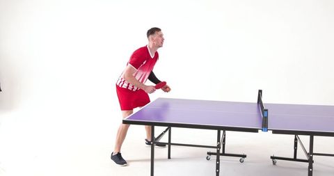 Male athlete engaged in intense ping pong training indoors