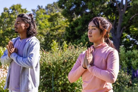 Multicultural couple practicing mindful meditation in sunlit park garden