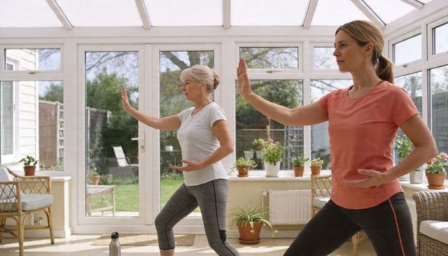 Practicing tai chi for balance and mindfulness by senior and adult women in sunroom