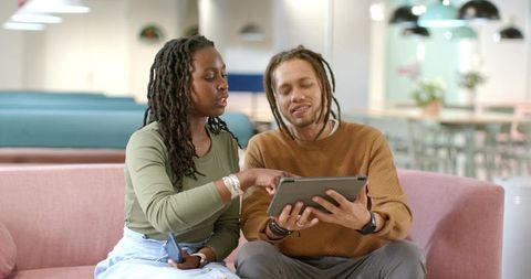 African American Colleagues Collaborating on Tablet in Modern Coworking Lounge