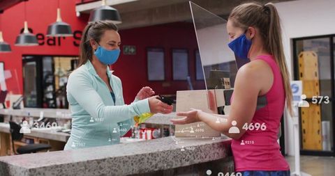 Gym receptionist scanning membership card with precautions