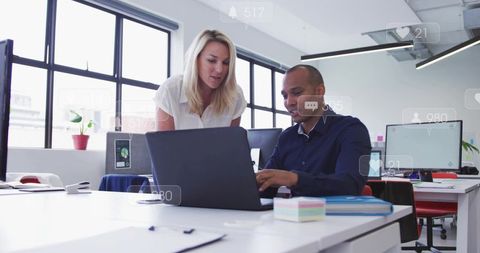 Colleagues Collaborating at Laptop in Bright Open-Plan Office, Mentoring and Strategizing