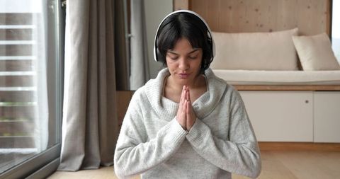 Woman Meditating at Home with Headphones in Peaceful Living Room