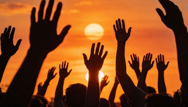 Sunset crowd raising hands in silhouette at outdoor concert