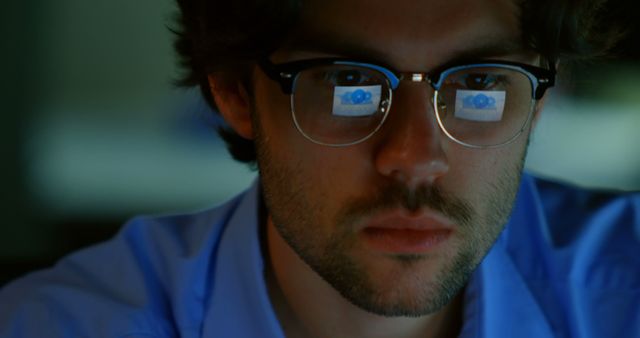 Young Caucasian man focused on his computer screen in a dimly lit office - Download Free Stock Photos Pikwizard.com