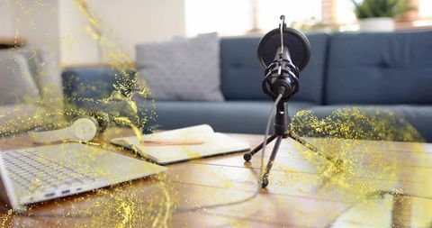 Recording podcast with condenser microphone and laptop on wooden table in cozy living room