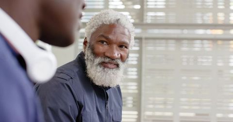 African American Senior Mentor Smiling in Office Conversation with Colleague