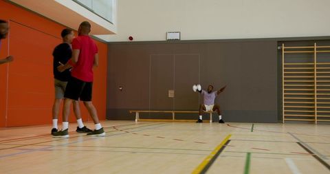 Athletes practicing on indoor gym court with bench and wall bars, team training