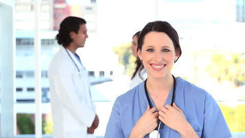 Smiling Nurse with Doctors in Background Bright Medical Setting