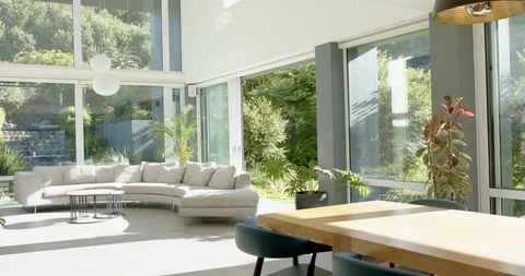 Sunlit modern living room featuring curved sectional and floor-to-ceiling windows