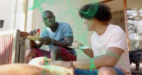 Friends enjoying casual outdoor meal on porch steps with dogs, summer patio gathering