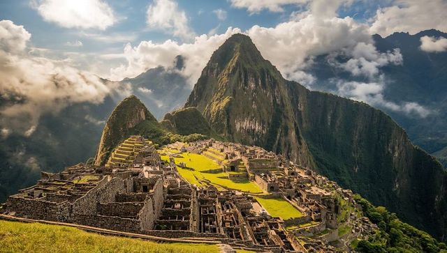 Sunlit machu picchu terraces perched atop andean mountain with dramatic cloudscape