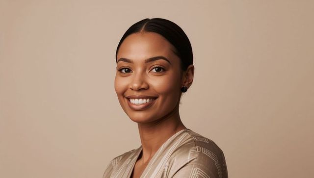 Smiling professional woman in beige blouse posing with warm smile on neutral background