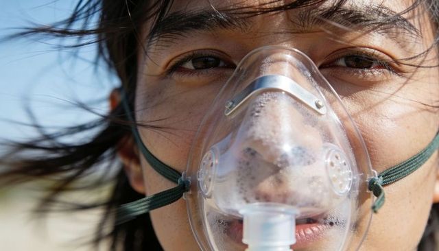 Closeup sunlit woman wearing oxygen mask with condensation and wind-blown hair