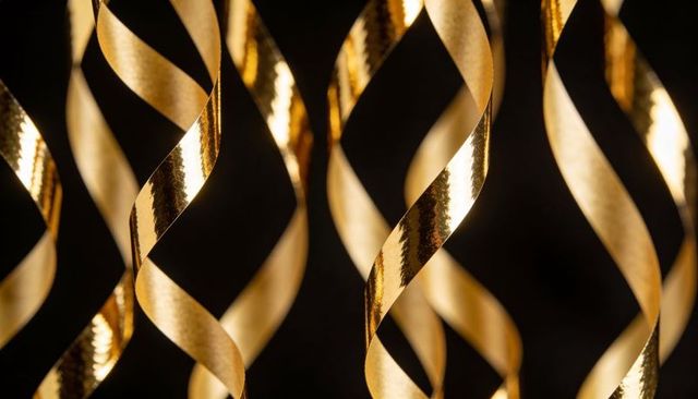 Shimmering gold spiral ribbons catching warm light against deep black background