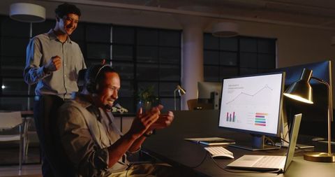 Business team celebrating success during data analysis night work