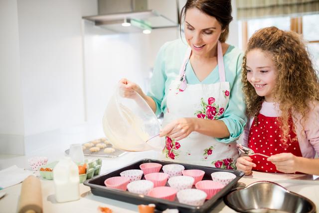 Mother and daughter preparing cupcake in kitchen at home