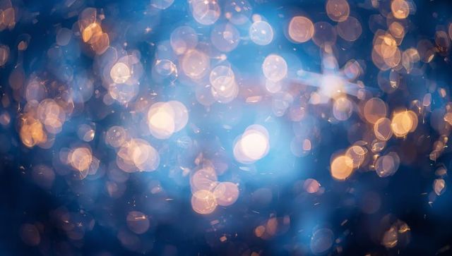 Dreamy blue bokeh sparkle with warm golden highlights, abstract festive light texture