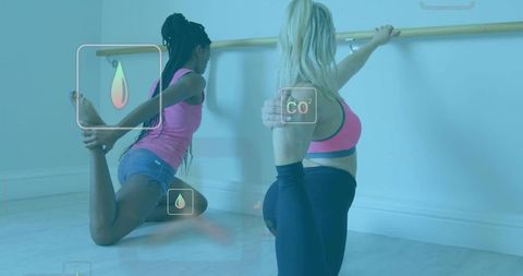 Female duo stretching at barre for flexibility and balance in minimalist fitness studio