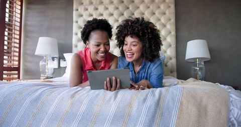 Diverse Female Couple Relaxing with Tablet Technology at Home