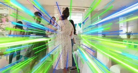 Woman hosting indoor celebration with friends in floral dress and neon light streaks