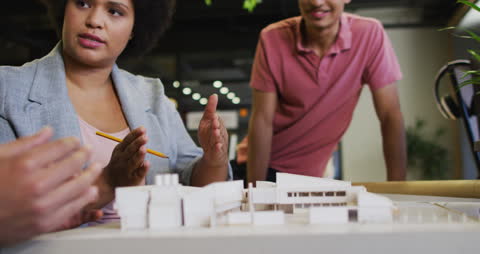 Diverse Coworkers Discussing Architectural Model in Modern Office