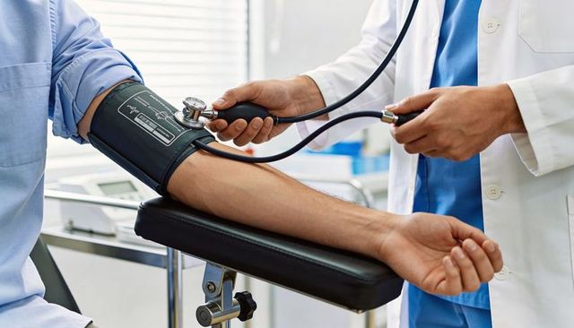 Clinician measuring blood pressure with stethoscope and sphygmomanometer on patient arm