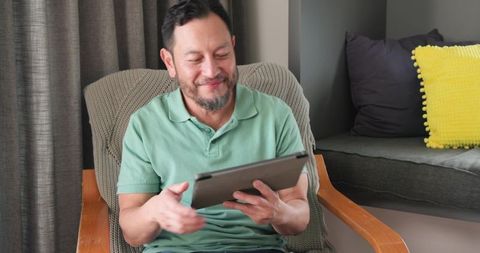 Happy Asian Man Using Tablet Relaxing at Home