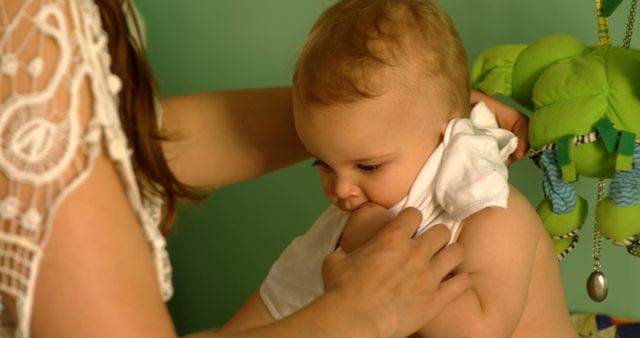 Mother Dressing Baby in White Shirt in Nursery - Download Free Stock Images Pikwizard.com