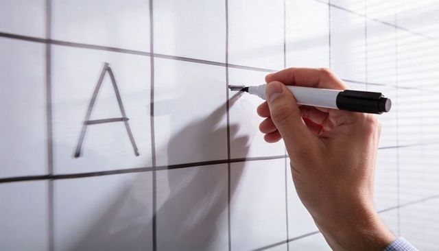 Hand writing on whiteboard grid with black marker for planning, presentation and collaboration