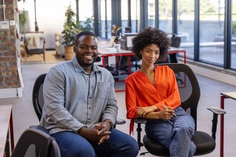 Colleagues collaborate in modern office with ergonomic chairs