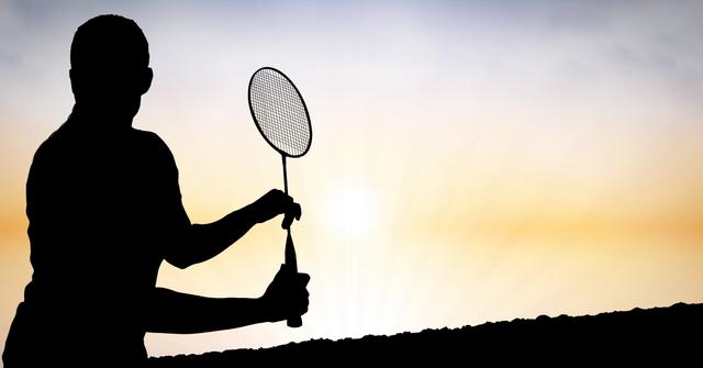 Silhouette of a man playing badminton during sunset, capturing the essence of outdoor sports and leisure activities. Ideal for use in fitness and sports promotions, healthy lifestyle campaigns, and recreational activity advertisements. The serene evening sky adds a calming backdrop, making it suitable for wellness and relaxation themes.