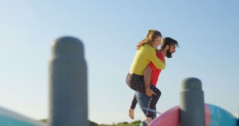 Couple Enjoying Piggyback Ride on Sunny Beach