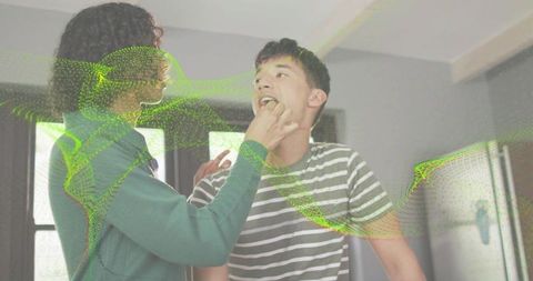 Nonbinary person feeding partner in kitchen, intimate modern couple sharing home moment