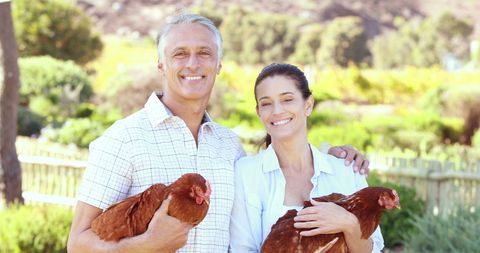 Happy Couple Embracing Farm Life with Chickens in Scenic Countryside - Download Free Stock Images Pikwizard.com