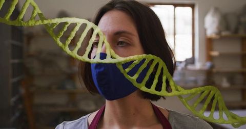 Pottery artist wearing face mask in ceramic studio with green dna strand overlay